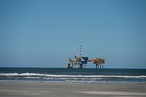 An offshore oil rig visible from a nearby beach in the Netherlands