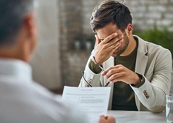 Man holding his head during a consultation across a desk