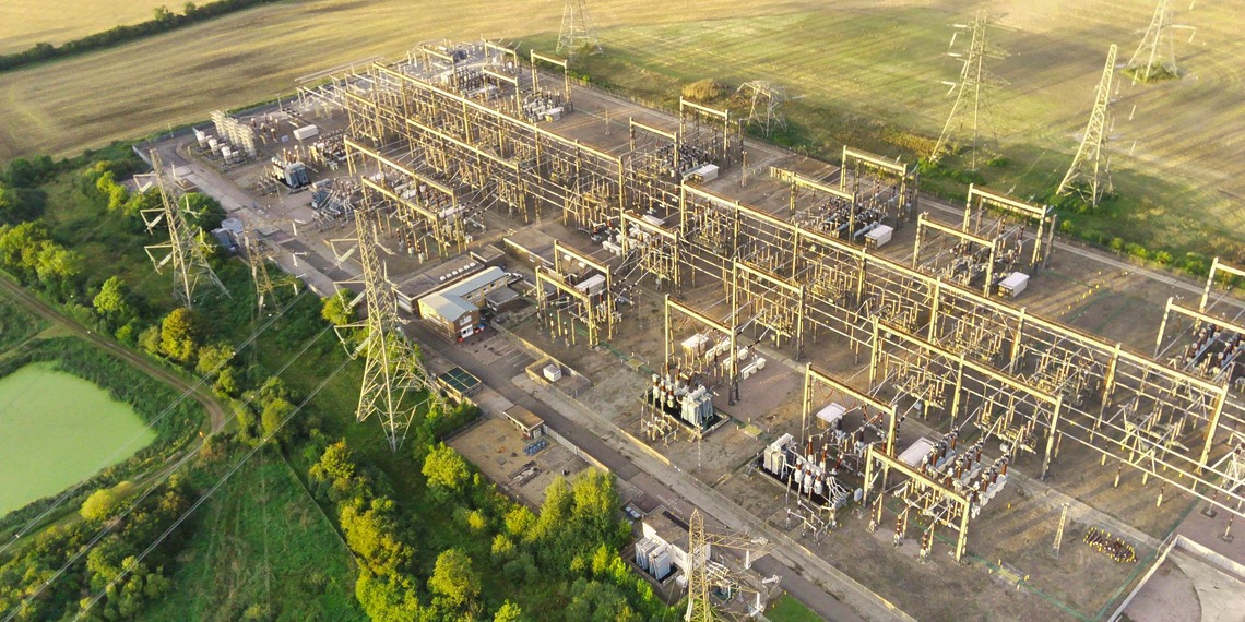 An aerial shot of a power station with greenery of rural England in the background