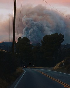 Thick smoke plume rising over a distant forested landscape