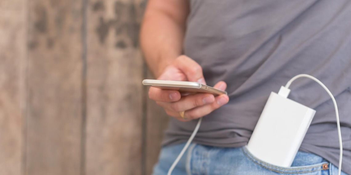 Person charging a smartphone with a portable power bank