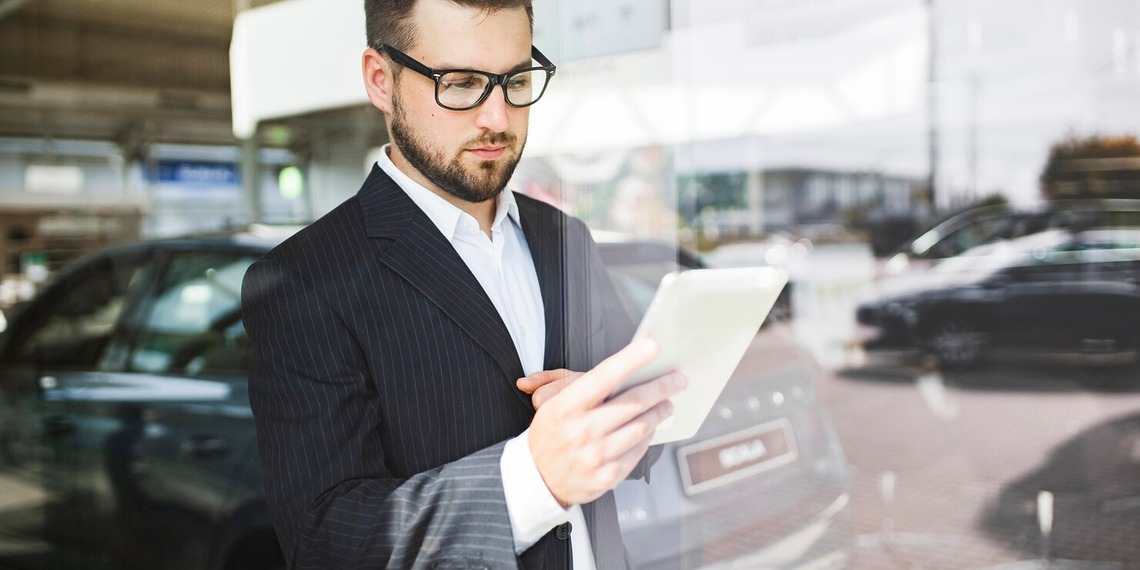 Business professional using a tablet in a vehicle showroom