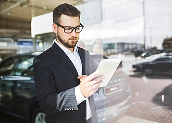 Business professional using a tablet in a vehicle showroom