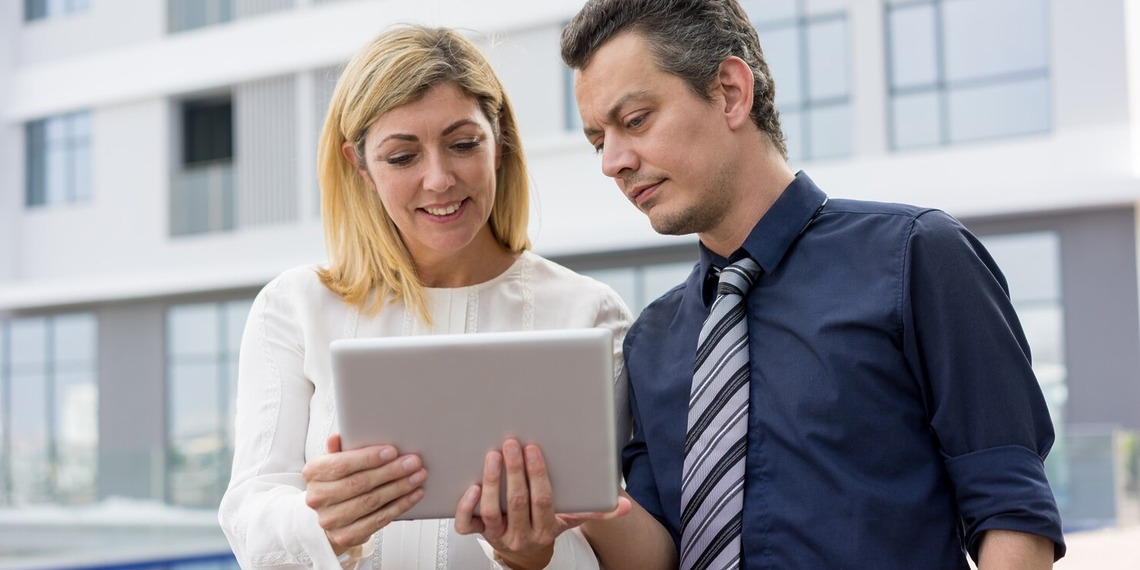 Property professionals reviewing a tablet outside a modern commercial building