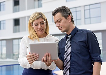 Property professionals reviewing a tablet outside a modern commercial building