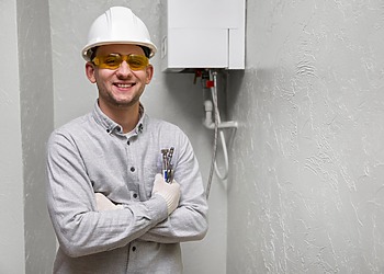 Technician standing beside a wall-mounted tankless water heater