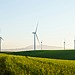 Wind turbines rising above a grassy field under an open sky