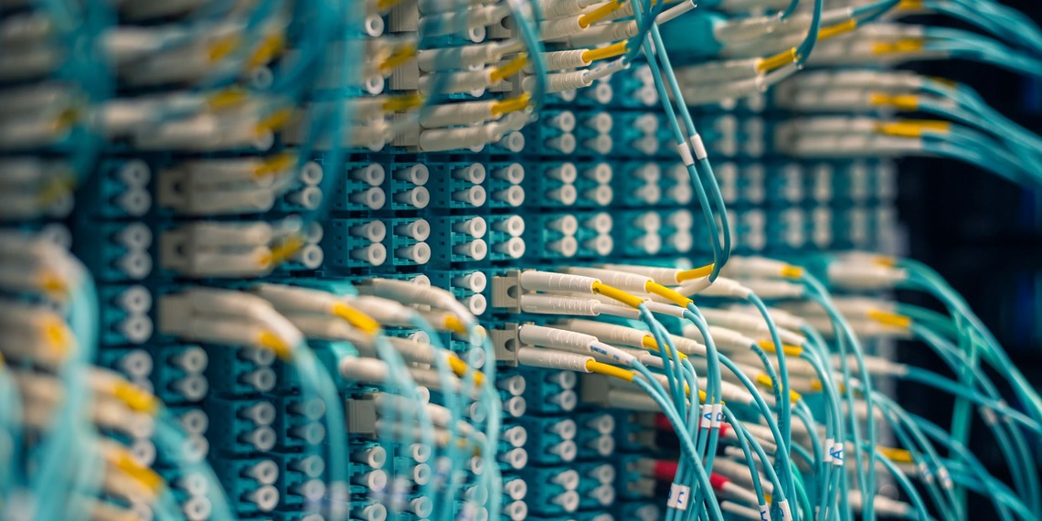 Blue, yellow, and white cables plugged into a patch panel in a server room.