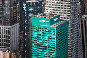 A teal blue Salesforce building surrounded by other high rise buildings in New York City.