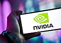 Close-up of a hand holding a smartphone showing the NVIDIA logo on screen with a blurred background.
