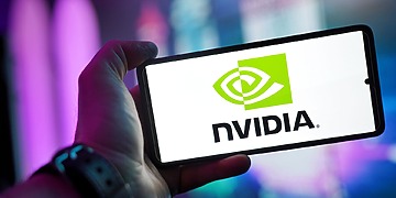 Close-up of a hand holding a smartphone showing the NVIDIA logo on screen with a blurred background.