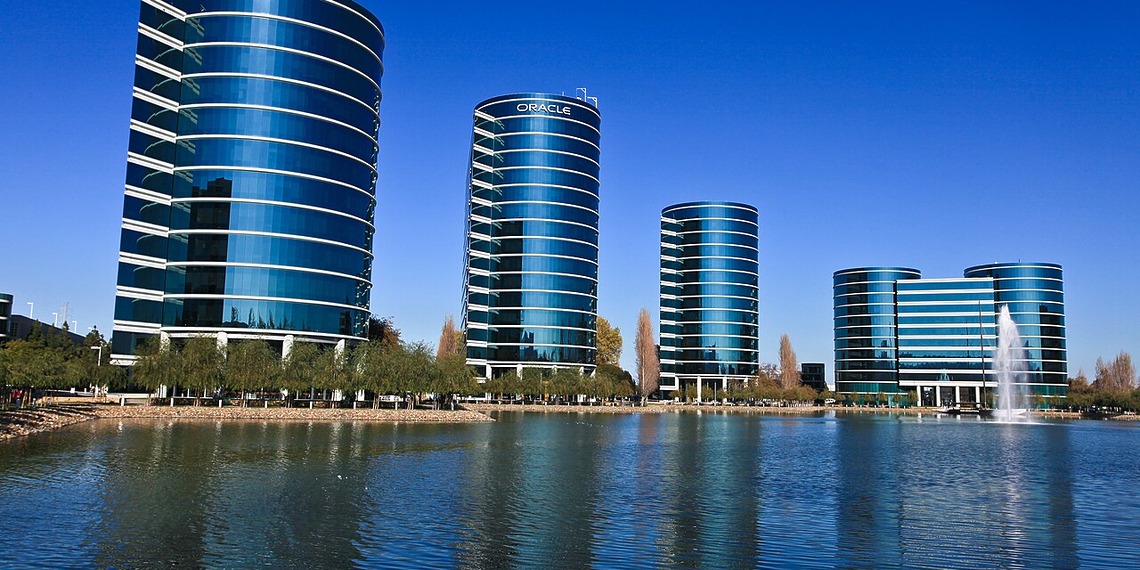 Four round corporate buildings viewed across a body of water.