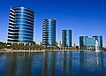 Four round corporate buildings viewed across a body of water.