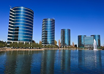 Four round corporate buildings viewed across a body of water.