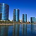 Four round corporate buildings viewed across a body of water.