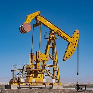A yellow and black oilfield crane near body of water during daytime