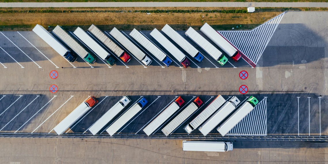 A aerial shot of semi-trucks parked diagonally in a lot.