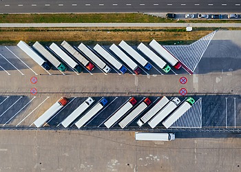 A aerial shot of semi-trucks parked diagonally in a lot.