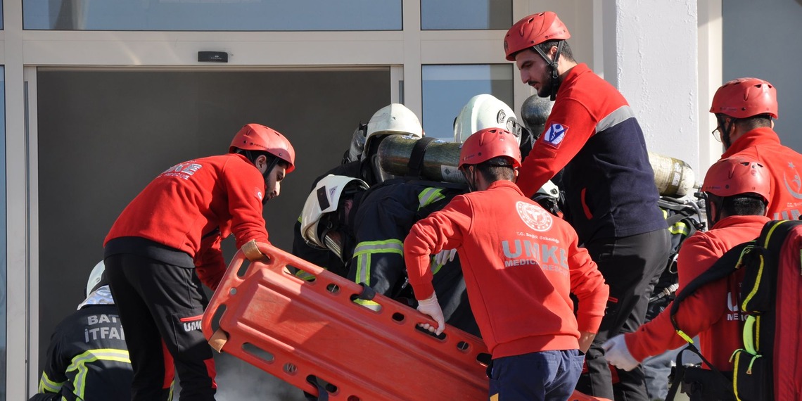 A group of firefighters and paramedics entering a smoking building for a rescue operation in Batman, Türkiye.