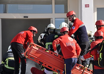 A group of firefighters and paramedics entering a smoking building for a rescue operation in Batman, Türkiye.