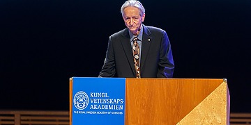 Geoffrey Hinton behind a speaker’s platform, accepting the Nobel Prize in 2024