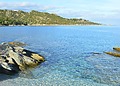 Clear blue water and rocky shoreline at Patrimonio, Corsica, on the Mediterranean coast.