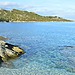 Clear blue water and rocky shoreline at Patrimonio, Corsica, on the Mediterranean coast.