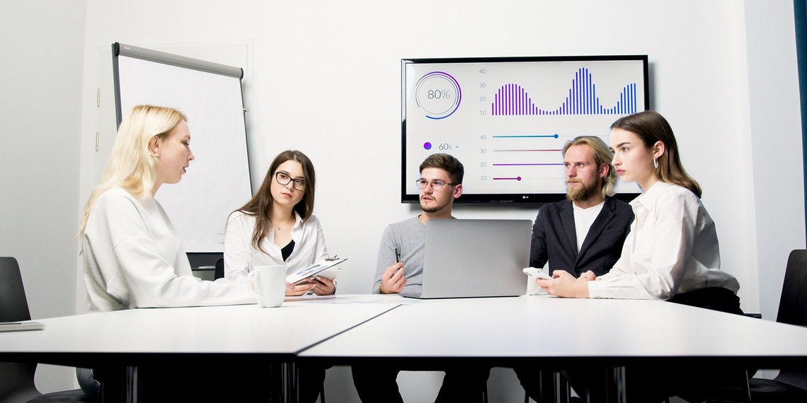 A network operations team monitors uptime dashboards in a corporate operations center.