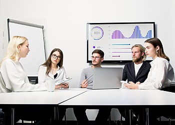 A network operations team monitors uptime dashboards in a corporate operations center.