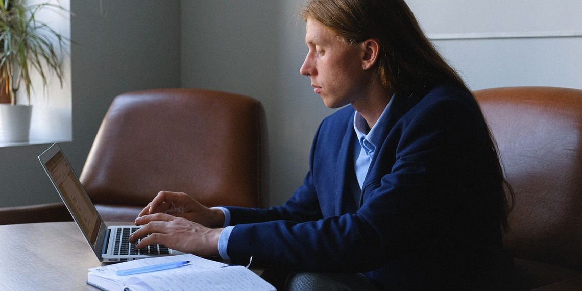 A male technical xxpert sitting at his office desk, typing on his laptop.