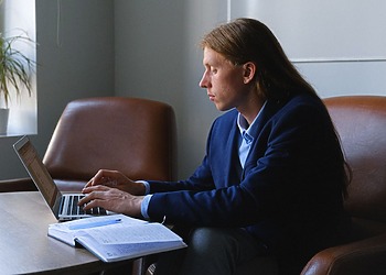 A male technical xxpert sitting at his office desk, typing on his laptop.