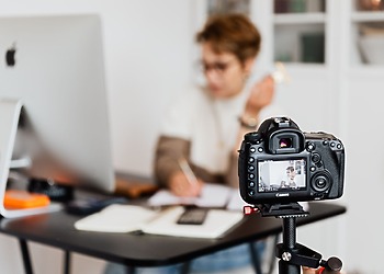 Woman in an office using a camera to create content, showcasing modern technology and creativity.