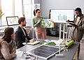 Business team reviewing data beside a solar panel and small wind turbine model