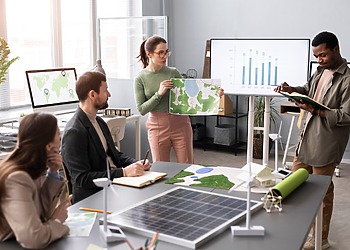 Business team reviewing data beside a solar panel and small wind turbine model