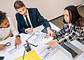 team of 3, two women and a man, sitting around a table in a meeting.