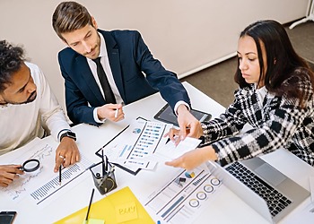 team of 3, two women and a man, sitting around a table in a meeting.