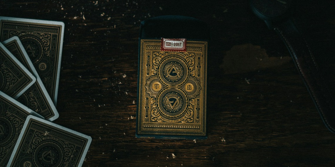 Antique hand painted playing cards laid out on a dark table