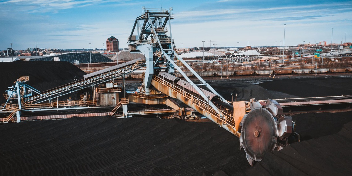 Machinery processing coal at a stockpile site.