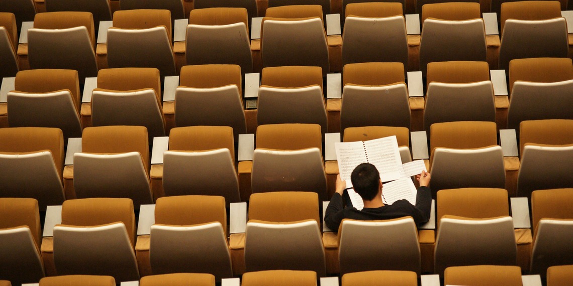 Person reading in an empty lecture hall.