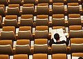 Person reading in an empty lecture hall.