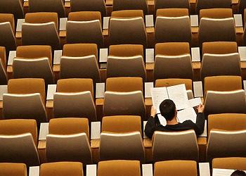 Person reading in an empty lecture hall.