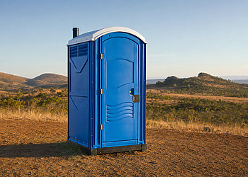Blue portable toilet standing in a dry rural landscape