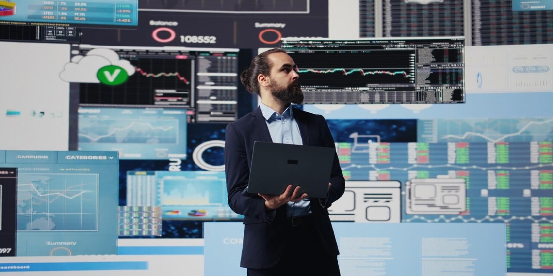 IT professional standing in front of multiple data dashboards and monitoring screens
