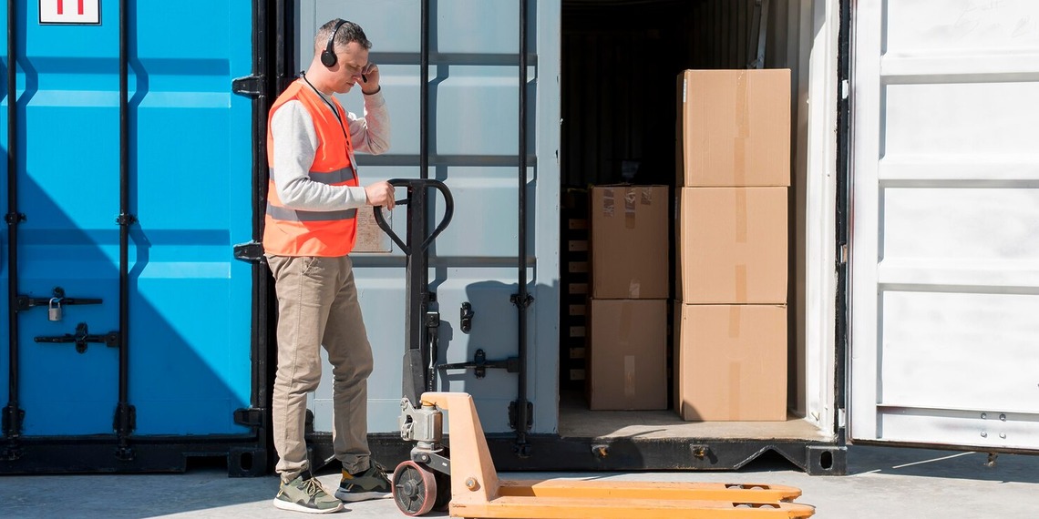 Worker standing beside an open shipping container with stored materials inside