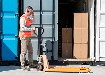 Worker standing beside an open shipping container with stored materials inside