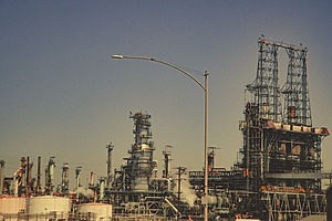 A large industrial refinery with pipes and towers under a clear blue sky. 