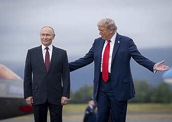 President Putin stands with his hands to his side; President Trump places one hand on Putin’s back and gestures with the other.
