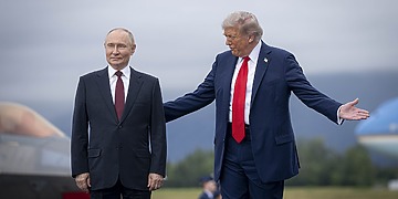 President Putin stands with his hands to his side; President Trump places one hand on Putin’s back and gestures with the other.