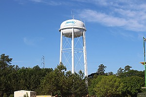 A white water tower against a blue sky.