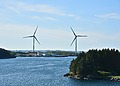 Two wind turbines along the Norwegian coastline near Haugesund, surrounded by the sea and green islands.
